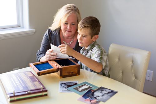 Mother and son looking at old letter and other family history articles